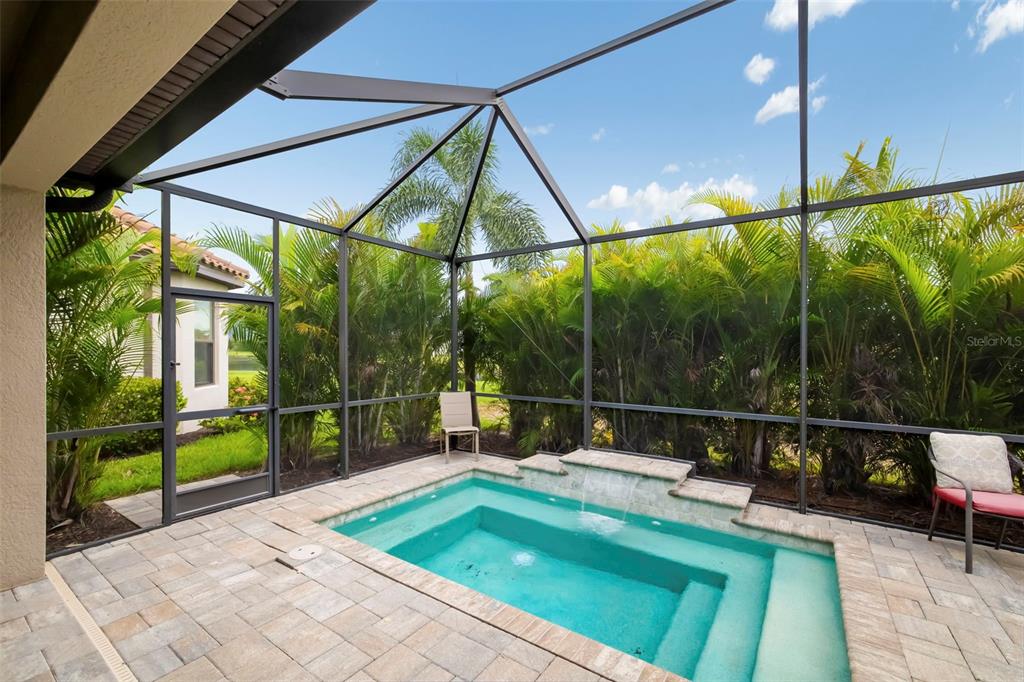 A screened-in patio features a small rectangular pool with a stone waterfall and paver decking — 4759 MOTTA COURT, BRADENTON, FL