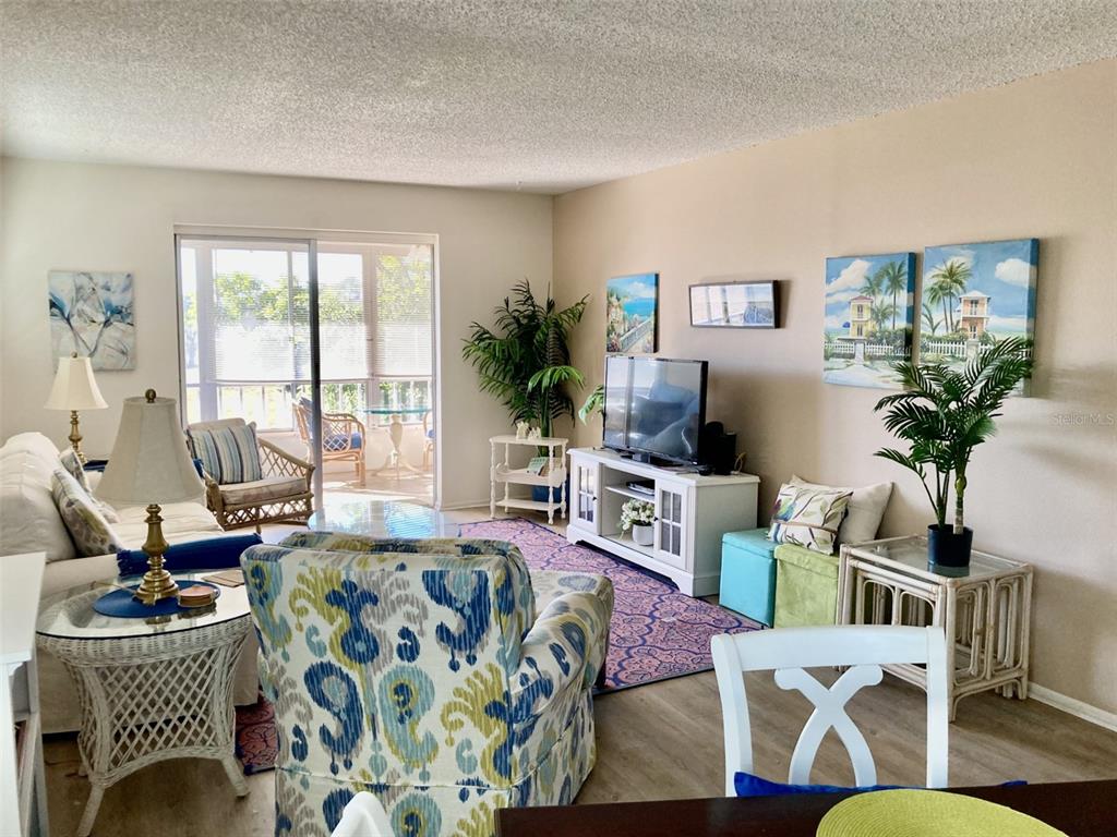 A living room features a patterned armchair, a white media console, and a glass-topped table — 304 47TH AVENUE DRIVE W UNIT 307, BRADENTON, FL