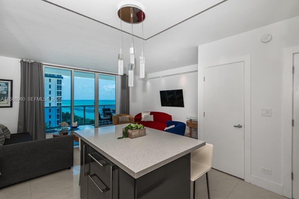 A kitchen island with a stone countertop overlooks a living area with ocean views — 2301 Collins Ave # 1111, Miami Beach FL 33139, MIAMI BEACH, FL