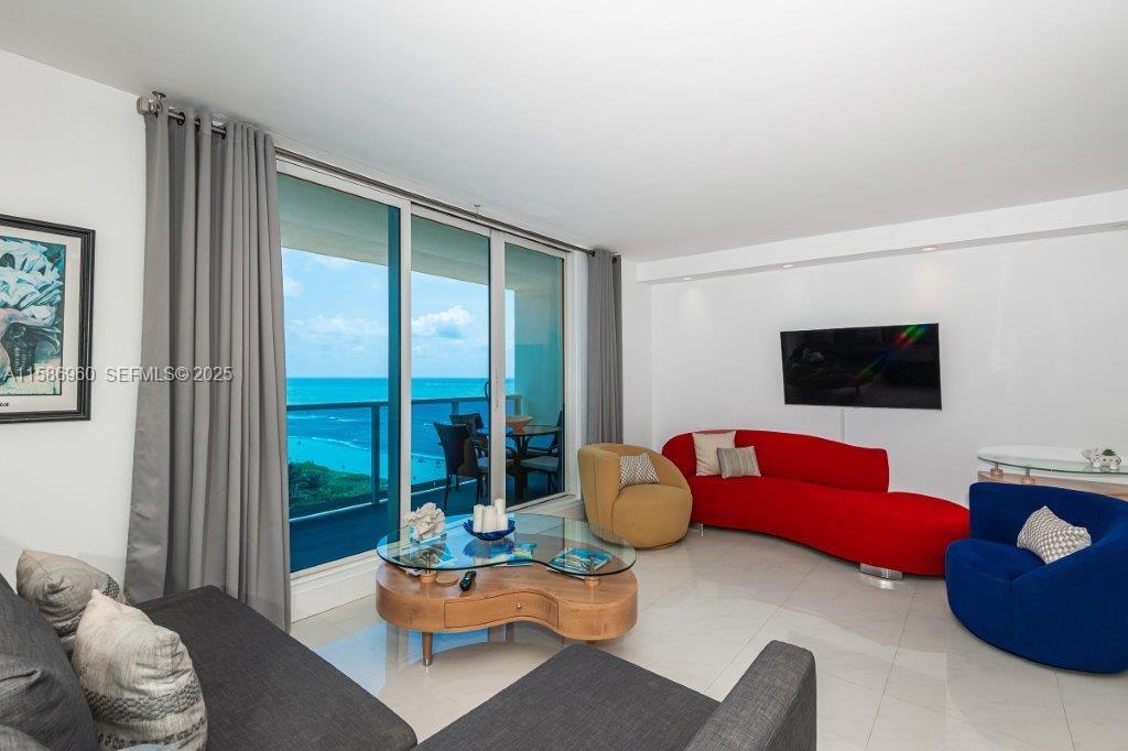 A living room features a red sofa, blue armchair, and a balcony with ocean views — 2301 Collins Ave # 1111, Miami Beach FL 33139, MIAMI BEACH, FL