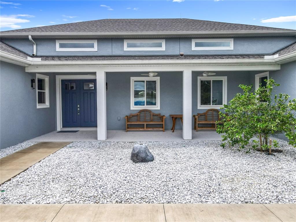 The exterior of a blue house features a covered porch with two benches and gravel — 10224 BAY LAKE ROAD, GROVELAND, FL