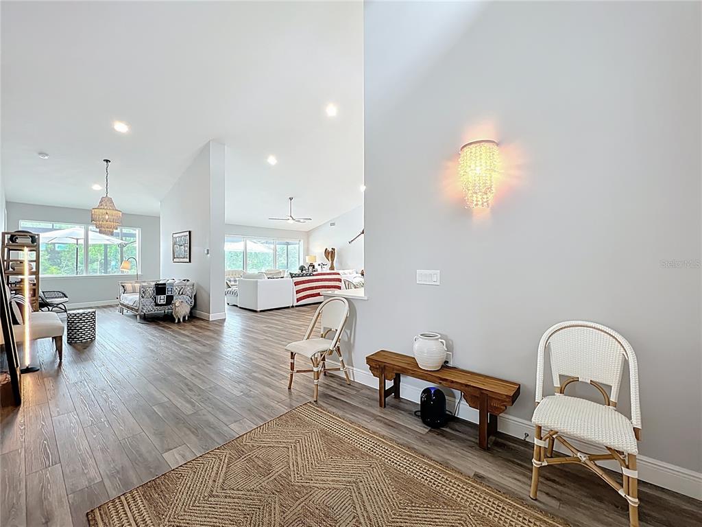 An open-concept living area features wood-look flooring, vaulted ceilings, and a wall-mounted crystal sconce — 10224 BAY LAKE ROAD, GROVELAND, FL