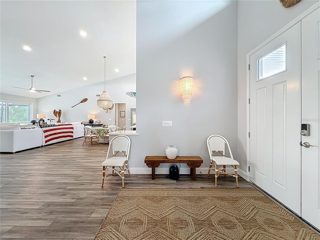 An entryway features a wood bench between two white chairs, leading into an open living area — 10224 BAY LAKE ROAD, GROVELAND, FL