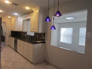 A kitchen features light-colored cabinets, dark countertops, tile flooring, and three hanging pendant lights — 305 COBLE DRIVE, LONGWOOD, FL