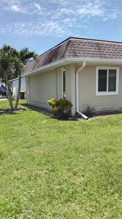 A living room with tile flooring, a gray sofa, a recliner, and a kitchen counter — 18579 ROBINSON AVENUE, PORT CHARLOTTE, FL