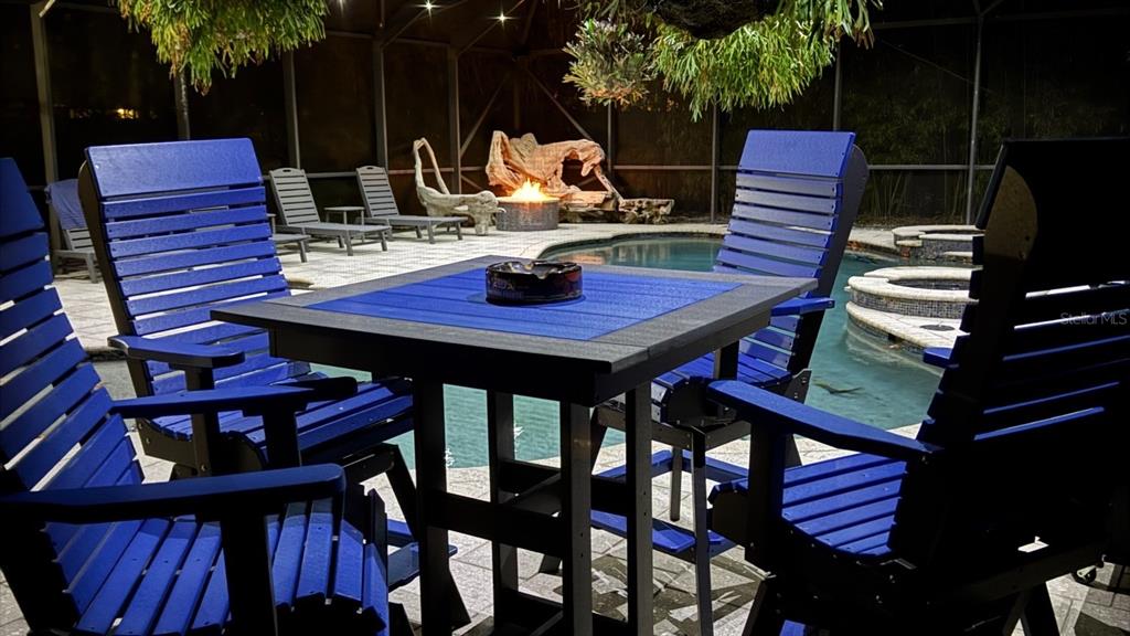 A patio with a blue table and chairs overlooks a swimming pool at night — 900 E 1ST AVENUE, NEW SMYRNA BEACH, FL