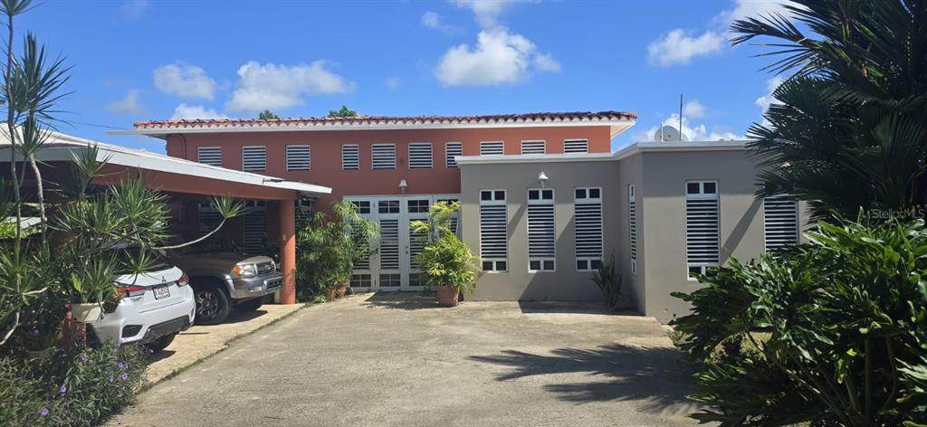 A two-tone house with a carport, a concrete driveway, and louvered windows under a blue sky — Carr. 137 km 9.9 BO. FRANQUES, MOROVIS, PR