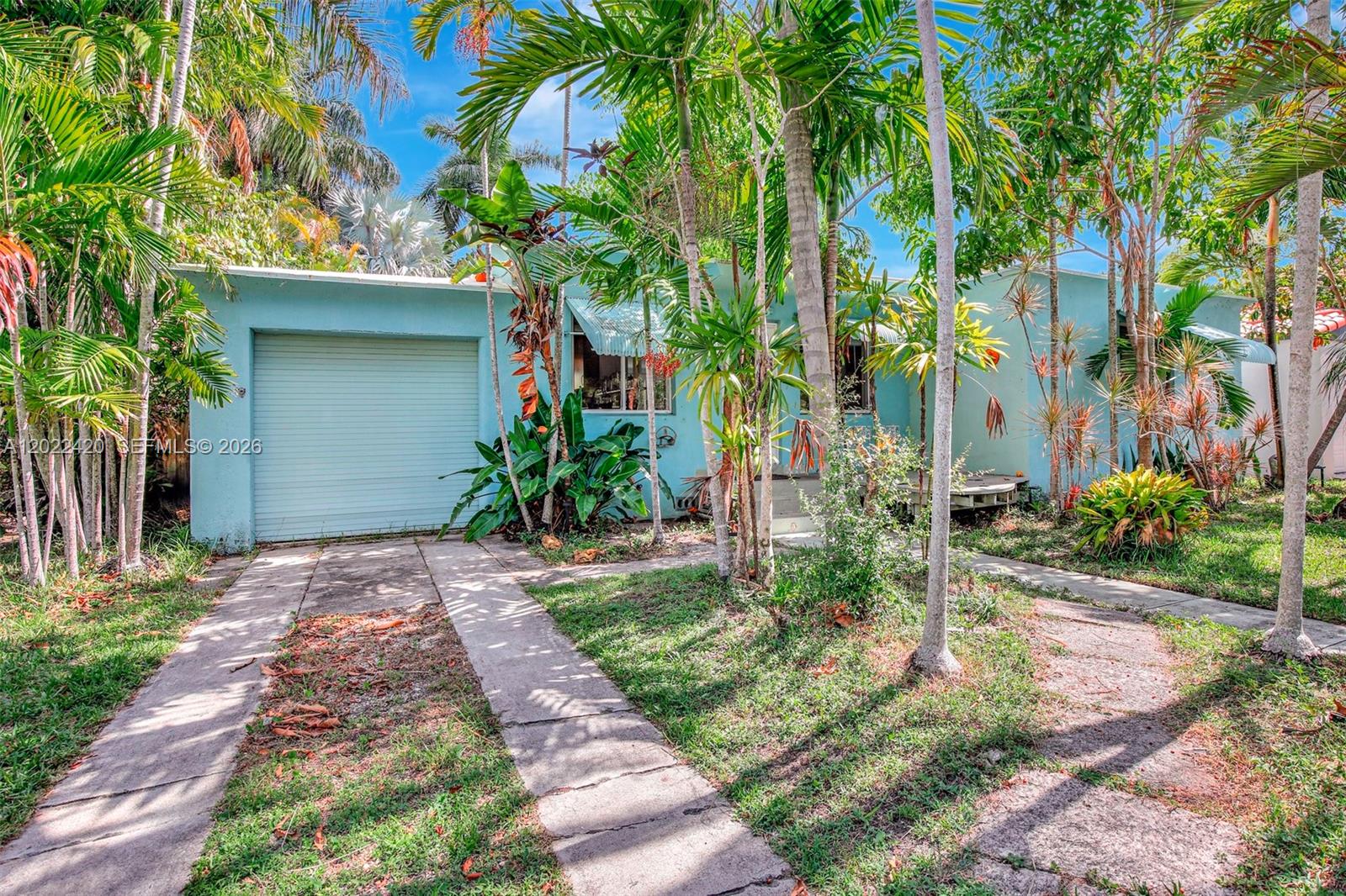 A light blue single-story house with a garage and palm trees in the front yard — 1523 Dewey St, Hollywood FL 33020, HOLLYWOOD, FL