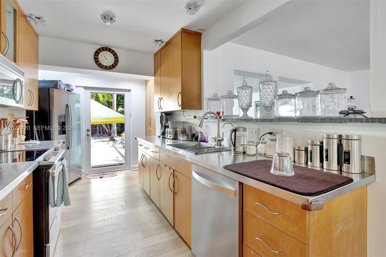 A kitchen features light wood cabinets, stainless steel countertops, and a glass door to a yard — 1523 Dewey St, Hollywood FL 33020, HOLLYWOOD, FL