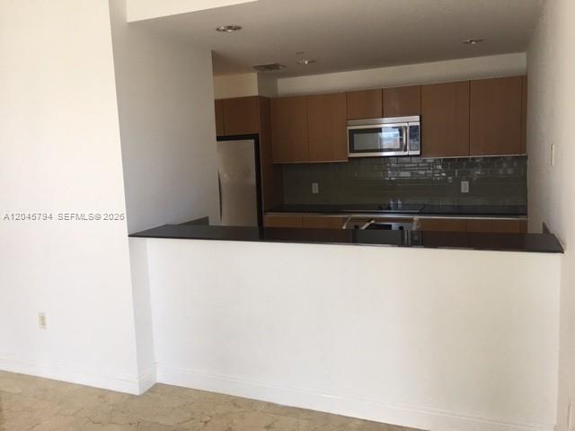 A kitchen features wood cabinets, a black countertop, and a stainless steel microwave — 1060 BRICKELL AV # 1901, Miami FL 33131, MIAMI, FL