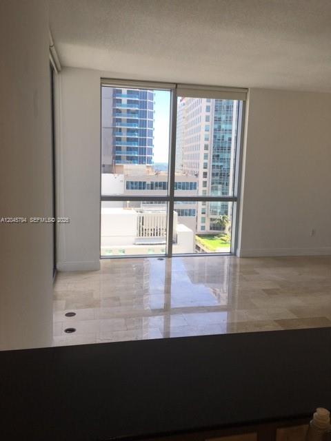 A room with light-colored tile flooring and a large window overlooking city buildings — 1060 BRICKELL AV # 1901, Miami FL 33131, MIAMI, FL