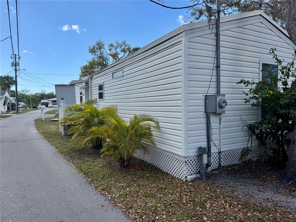 The exterior side of a white mobile home features vinyl siding and lattice skirting — 15010 113TH AVENUE N UNIT 48, LARGO, FL