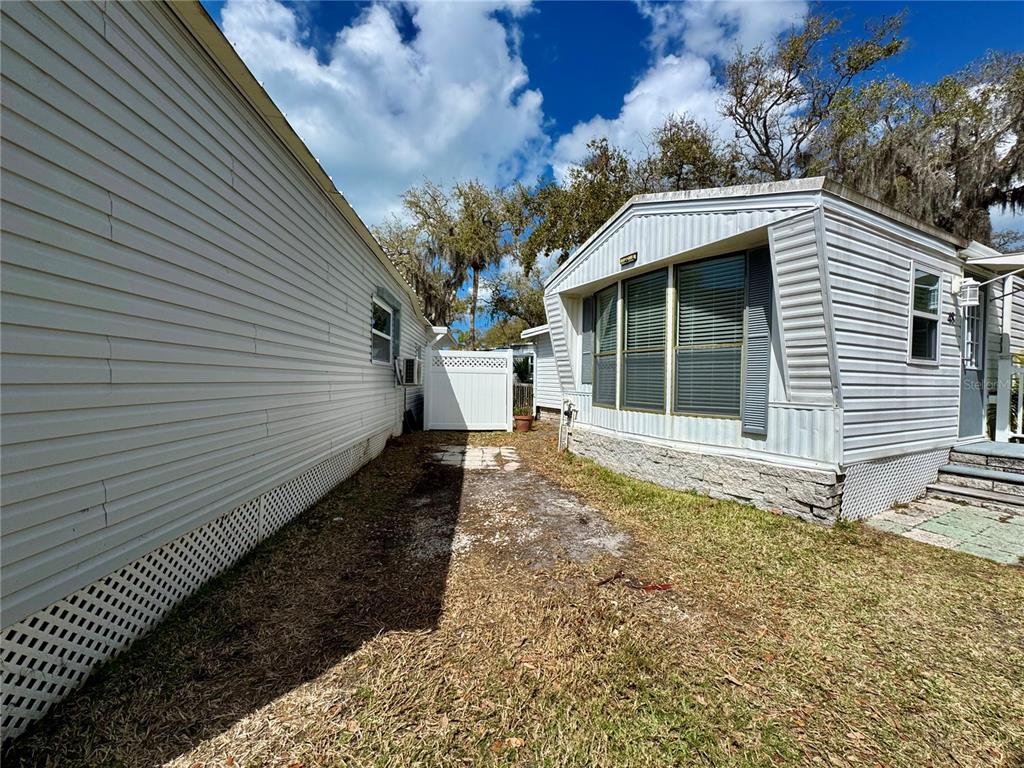 The exterior view shows the side of a mobile home with a small grassy yard — 15010 113TH AVENUE N UNIT 48, LARGO, FL