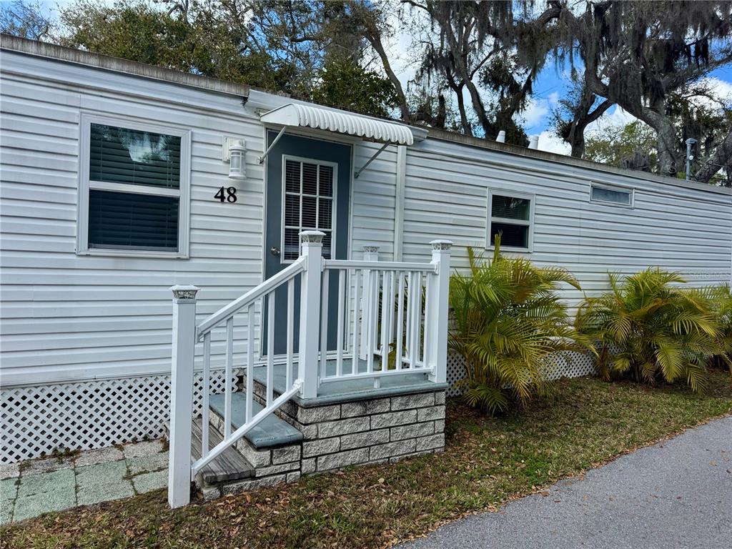 The exterior of a white mobile home features a small staircase with a white railing — 15010 113TH AVENUE N UNIT 48, LARGO, FL