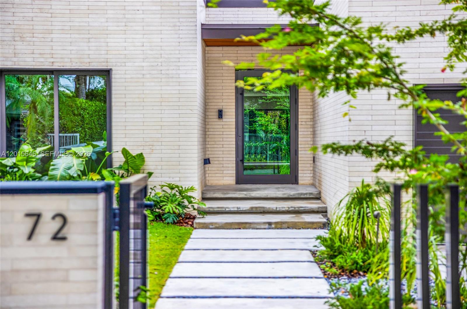 A modern house entrance features a glass door, concrete steps, and a stone walkway — 72 W Shore Dr W, Miami FL 33133, MIAMI, FL