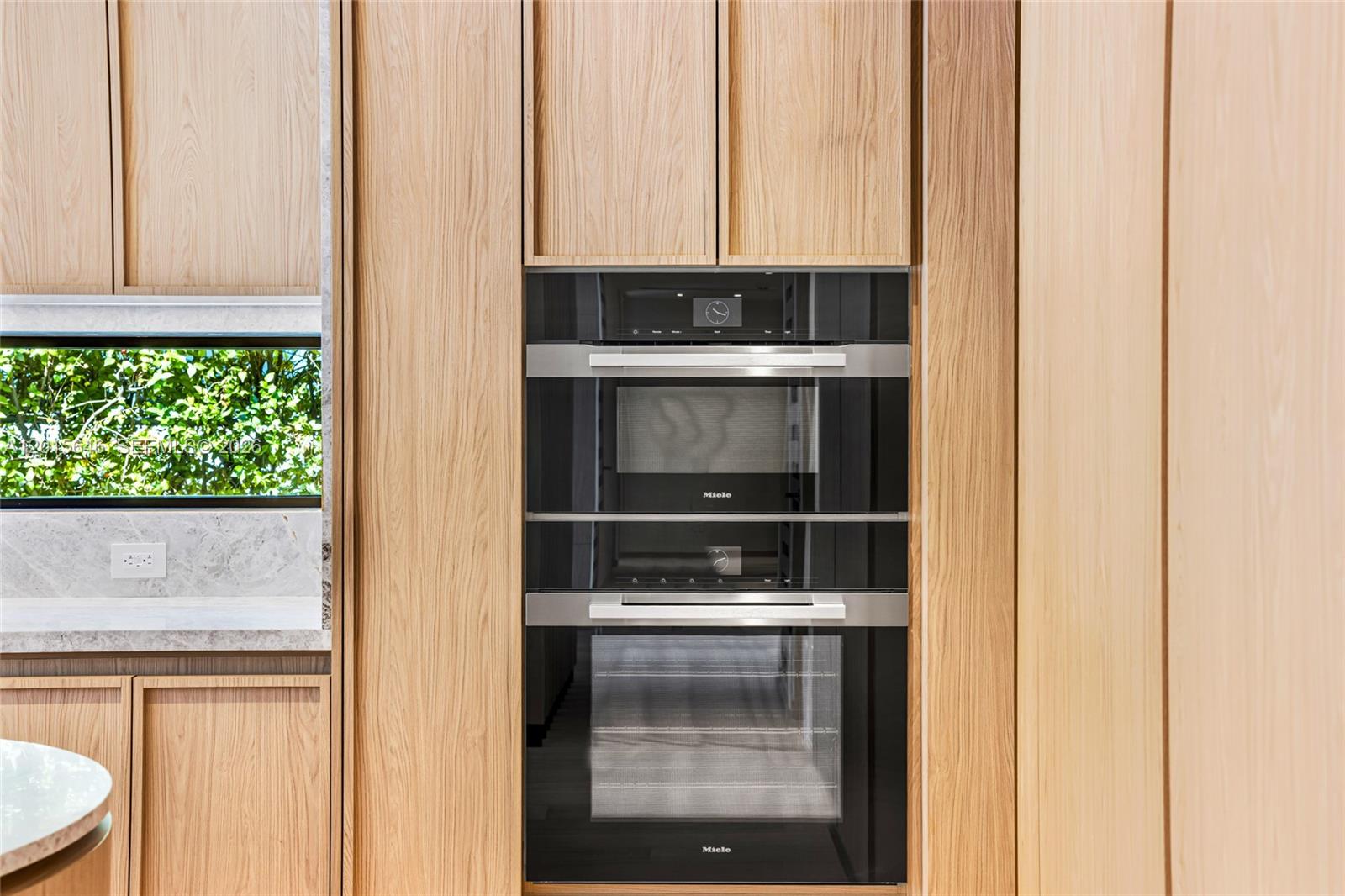 A kitchen features light wood cabinetry and a stacked Miele oven unit — 72 W Shore Dr W, Miami FL 33133, MIAMI, FL