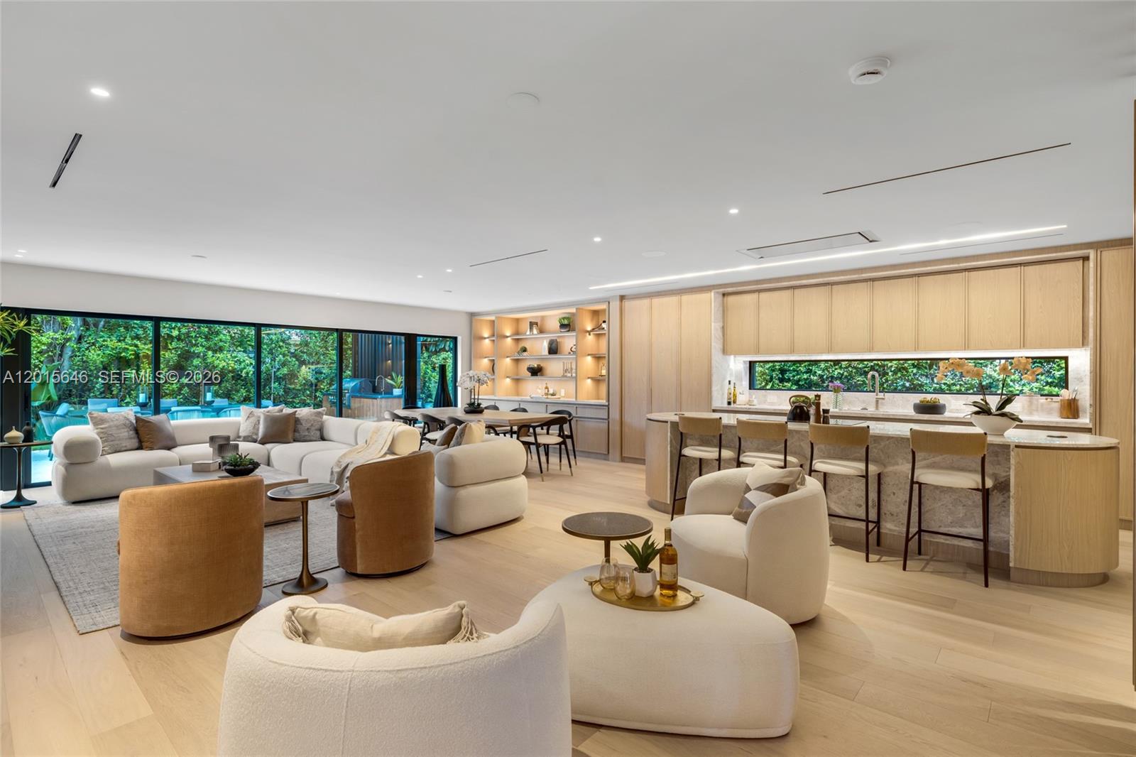 An open-concept living and kitchen area features light wood floors, neutral furniture, and floor-to-ceiling windows — 72 W Shore Dr W, Miami FL 33133, MIAMI, FL