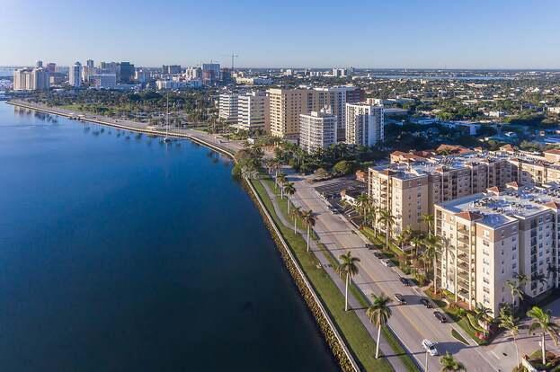 An aerial view shows a coastal road lined with palm trees and multi-story apartment buildings — 1805 N Flagler Drive # 107, West Palm Beach FL 33407, WEST PALM BEACH, FL