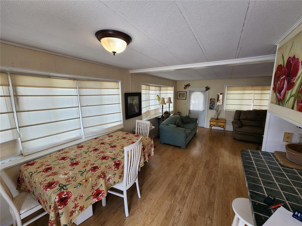 A dining area with a floral tablecloth transitions into a living room with wood flooring — 305 BATAN COURT, BRADENTON, FL