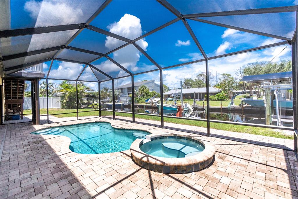 A screened-in patio features a swimming pool, a raised hot tub, and brick pavers — 9150 PINE COVE DRIVE, ENGLEWOOD, FL