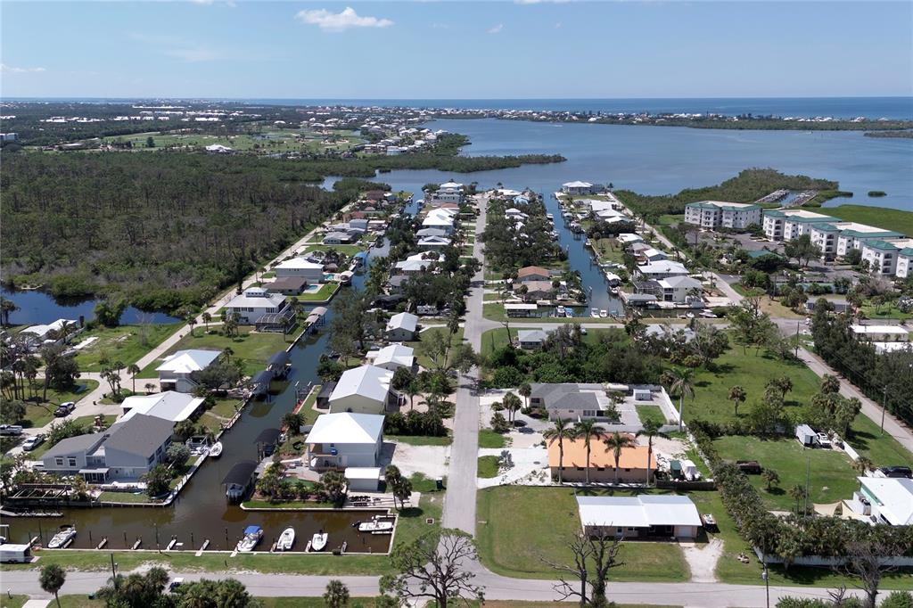 An aerial view shows waterfront homes along a canal leading to a large bay — 9150 PINE COVE DRIVE, ENGLEWOOD, FL
