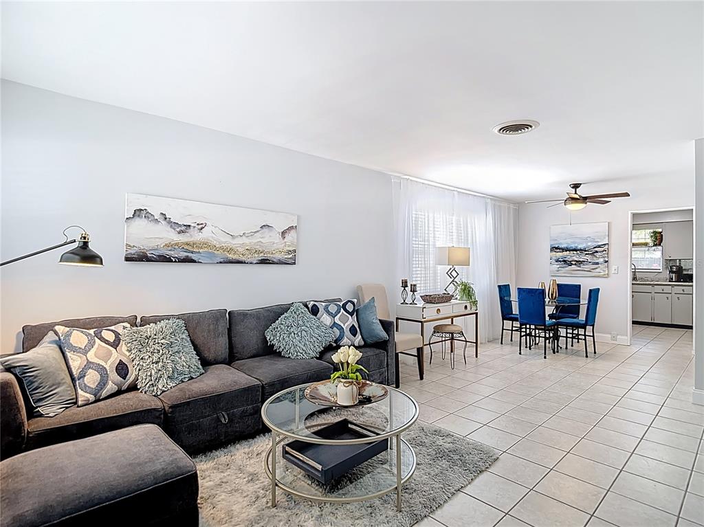 A living room and dining area feature gray tile floors, a sectional sofa, and furniture — 220 SE JEFFERSON CIRCLE N, ST PETERSBURG, FL