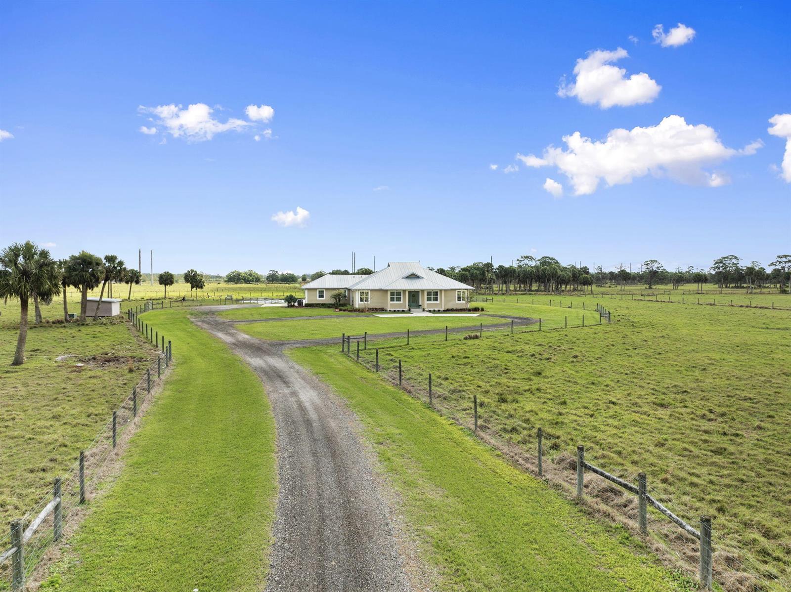 An aerial view shows a single-story house with a metal roof and a gravel driveway — 1720 S Brocksmith Road, Fort Pierce FL 34945, FORT PIERCE, FL