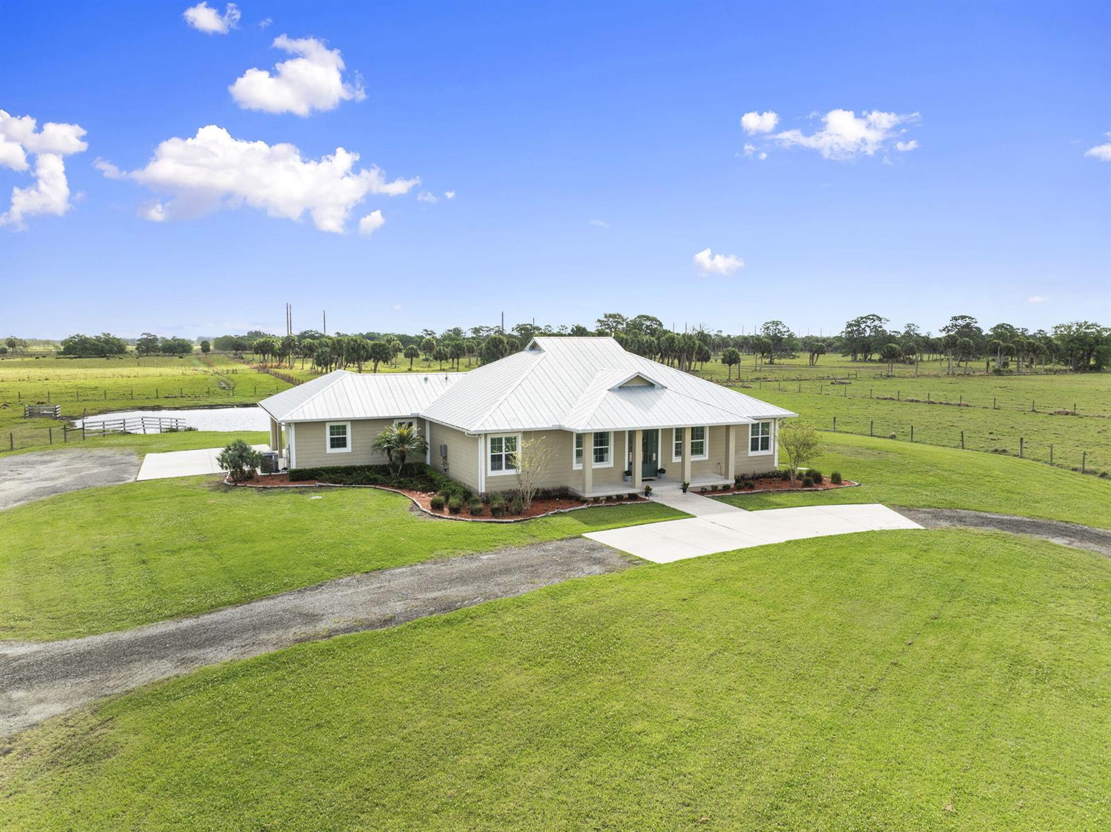 An aerial view of a single-story house with a metal roof on a grassy lot — 1720 S Brocksmith Road, Fort Pierce FL 34945, FORT PIERCE, FL