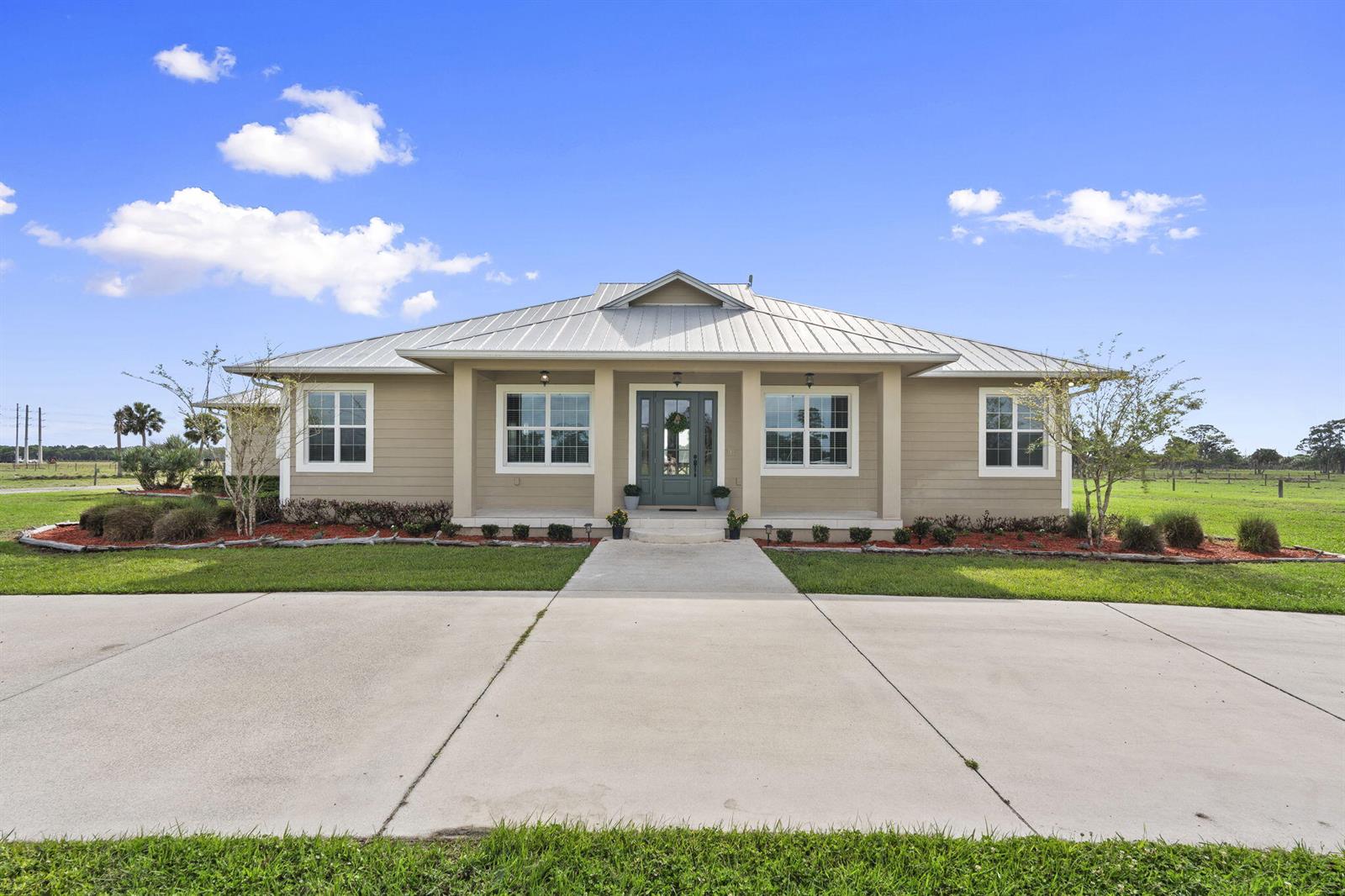 A single-story house with a metal roof, tan siding, and a concrete driveway — 1720 S Brocksmith Road, Fort Pierce FL 34945, FORT PIERCE, FL