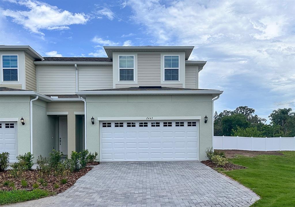 A two-story townhouse exterior features a light green stucco facade, a paved driveway, and garage — 24101 MANUMA STREET UNIT Seminole 2508, ST CLOUD, FL
