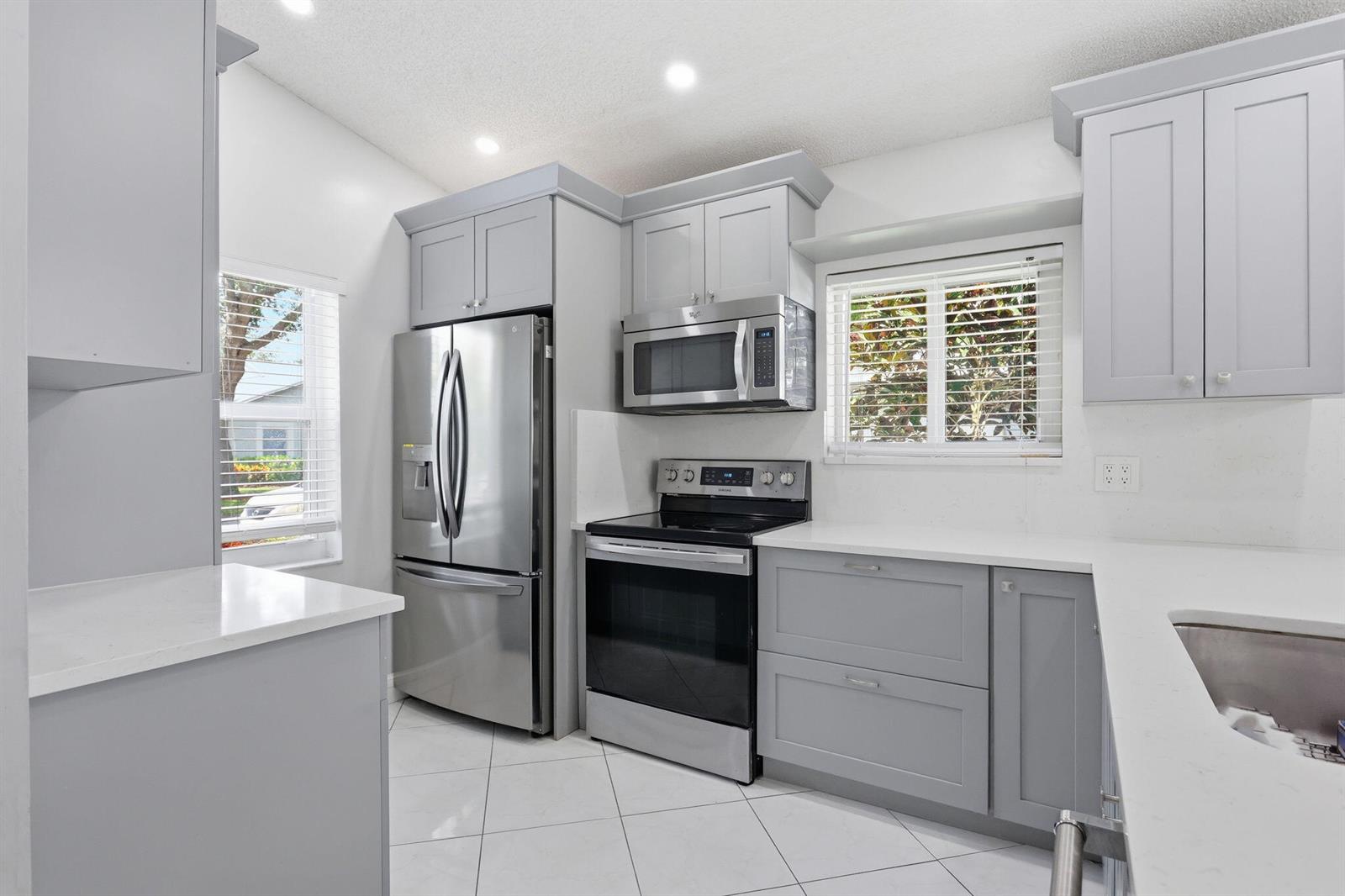 A kitchen features gray cabinets, stainless steel appliances, white countertops, and white tile flooring — 8621 Jasmine Way, Boca Raton FL 33496, BOCA RATON, FL
