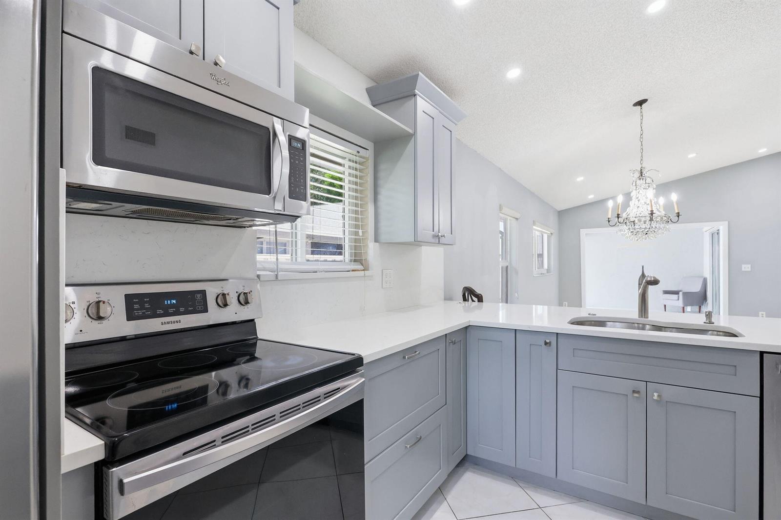 A kitchen with light blue cabinets, stainless steel appliances, and white countertops — 8621 Jasmine Way, Boca Raton FL 33496, BOCA RATON, FL
