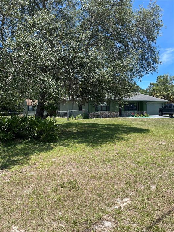 A single-story house with a stone facade and a garage sits behind a large tree — 7223 S SESAME STREET TERRACE, HOMOSASSA, FL