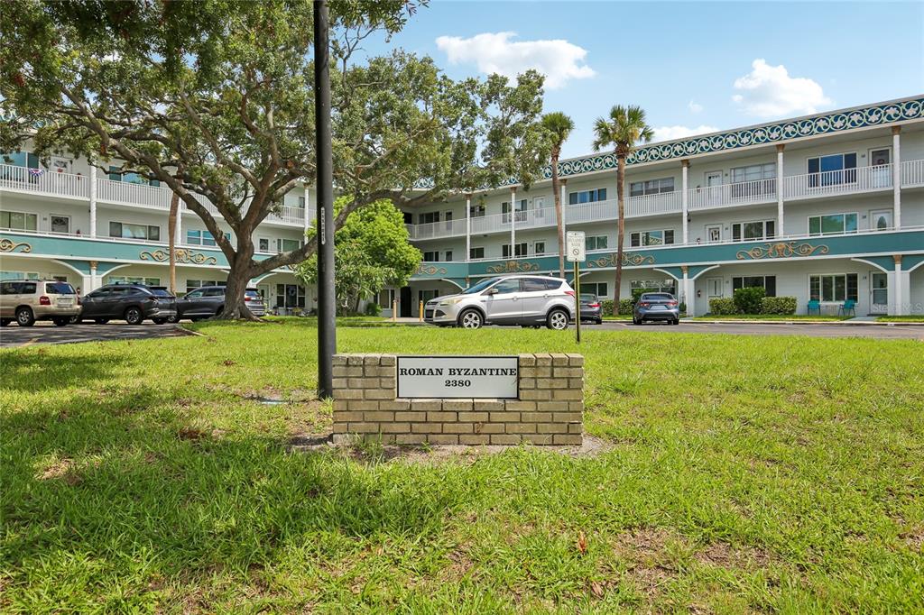 A brick sign for Roman Byzantine stands in front of a multi-story apartment building — 2380 WORLD PARKWAY BOULEVARD UNIT 40, CLEARWATER, FL