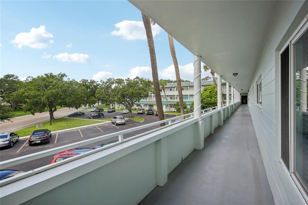 An outdoor walkway overlooks a parking lot with several cars and palm trees — 2380 WORLD PARKWAY BOULEVARD UNIT 40, CLEARWATER, FL
