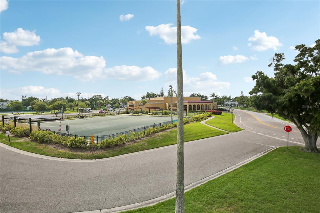 An outdoor view of a fenced green court, a building, and a paved road — 2380 WORLD PARKWAY BOULEVARD UNIT 40, CLEARWATER, FL