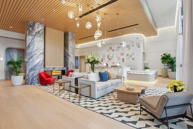 A modern hotel lobby features a seating area with sofas, armchairs, and a geometric area rug — 3015 S YSABELLA AVENUE UNIT 1504, TAMPA, FL
