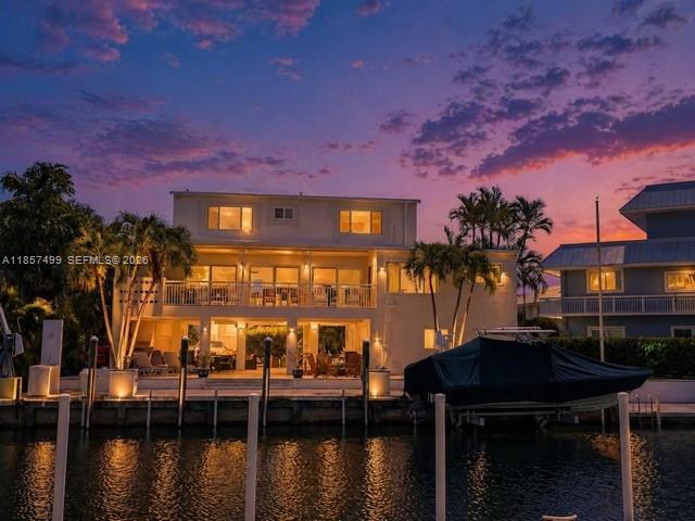 A multi-story house with striped awnings is illuminated at dusk above a paved driveway — 122 Court Contessa, Islamorada FL 33036, ISLAMORADA, FL