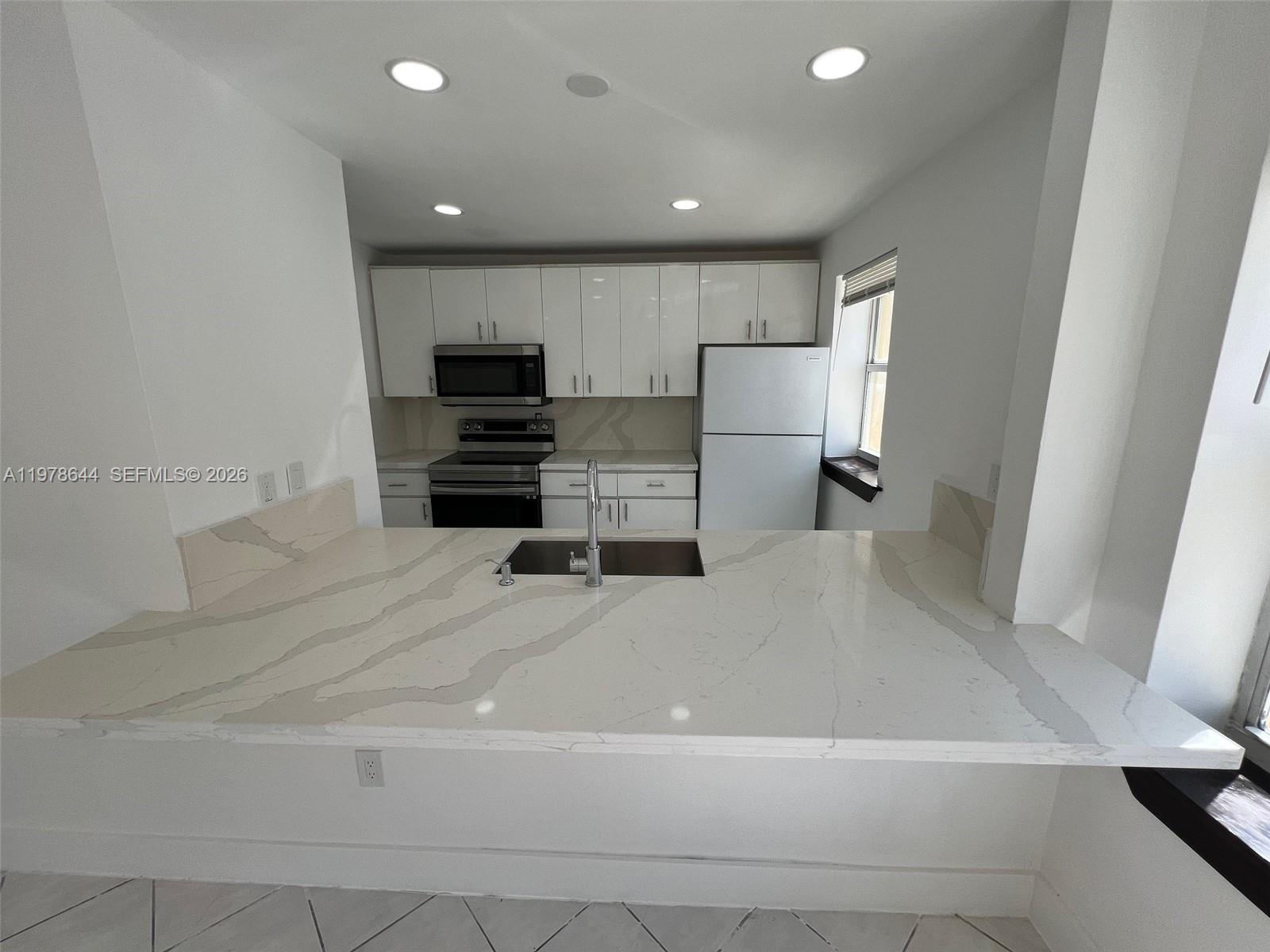 A kitchen features white cabinets, stainless steel appliances, and a white quartz countertop island — 1308 Drexel Ave # 103, Miami Beach FL 33139, MIAMI BEACH, FL