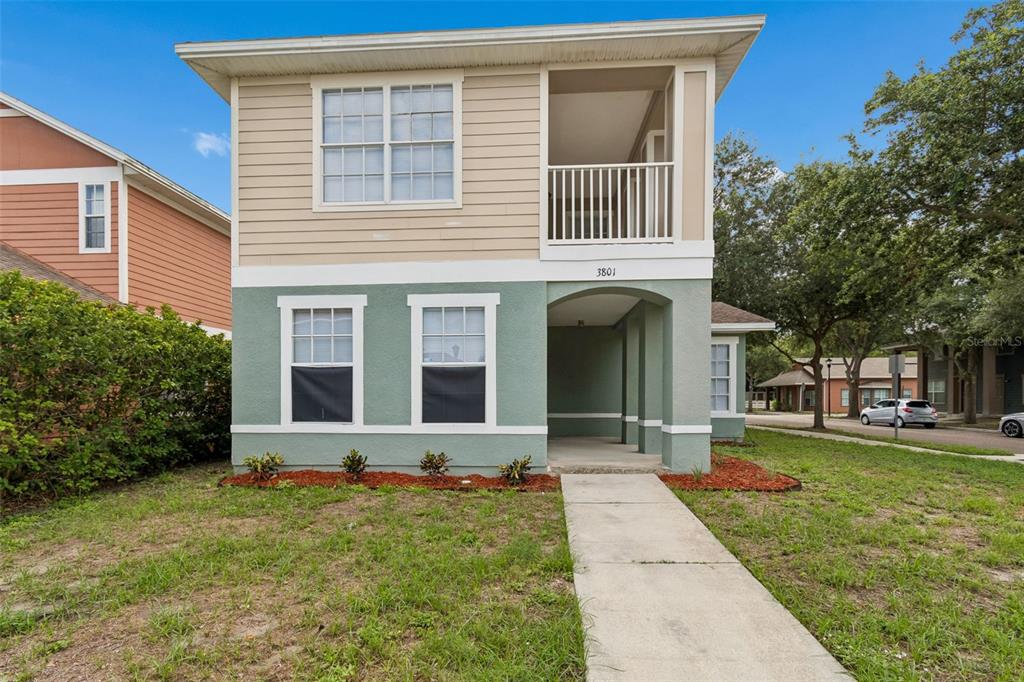 A two-story house with tan siding, a green stucco ground floor, and a covered entryway — 3801 MACHADO STREET, TAMPA, FL