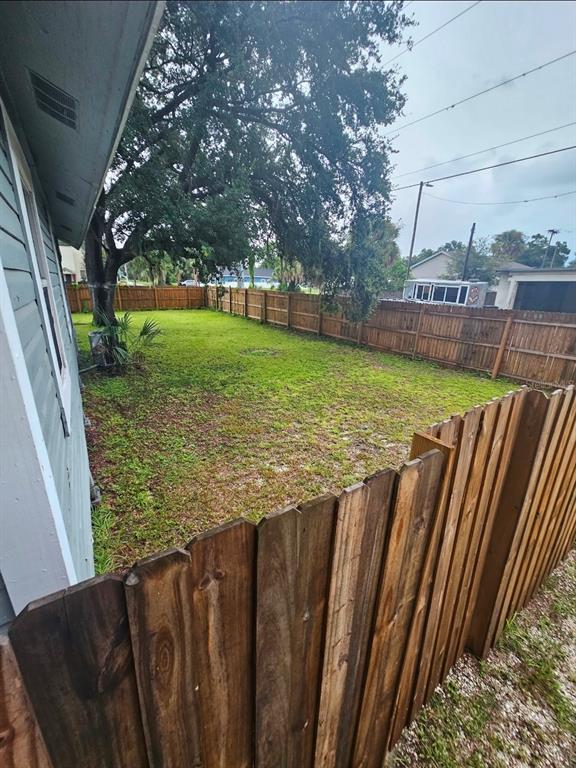 A fenced-in backyard with a grassy lawn and a large tree next to a house — 2634 E 26TH AVENUE, TAMPA, FL