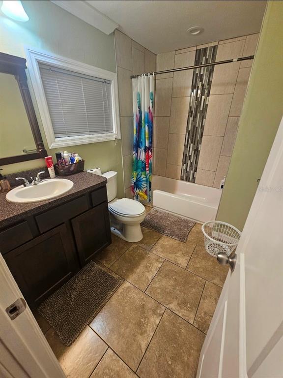 A bathroom features a dark wood vanity, a tiled shower-tub combination, and tan floor tiles — 2634 E 26TH AVENUE, TAMPA, FL