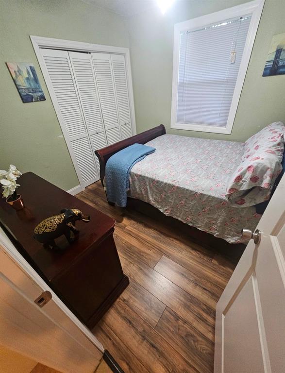 A bedroom features a bed, a dresser with an elephant figurine, and wood-look flooring — 2634 E 26TH AVENUE, TAMPA, FL