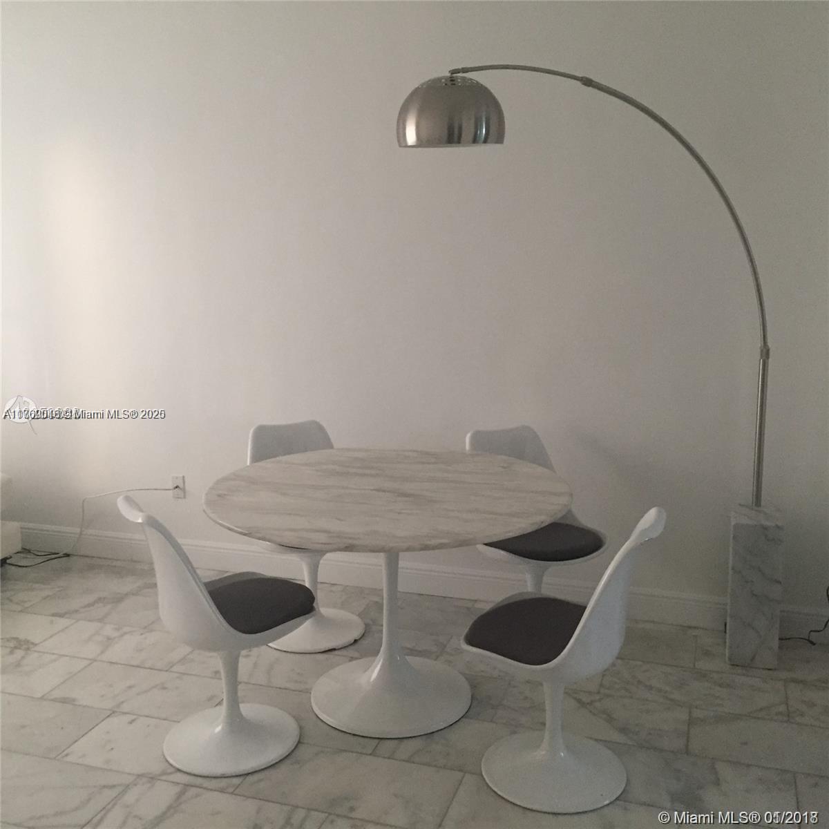 A dining area features a round marble table, four white tulip chairs, and an arched floor lamp — 918 Jefferson Ave # 2, Miami Beach FL 33139, MIAMI BEACH, FL