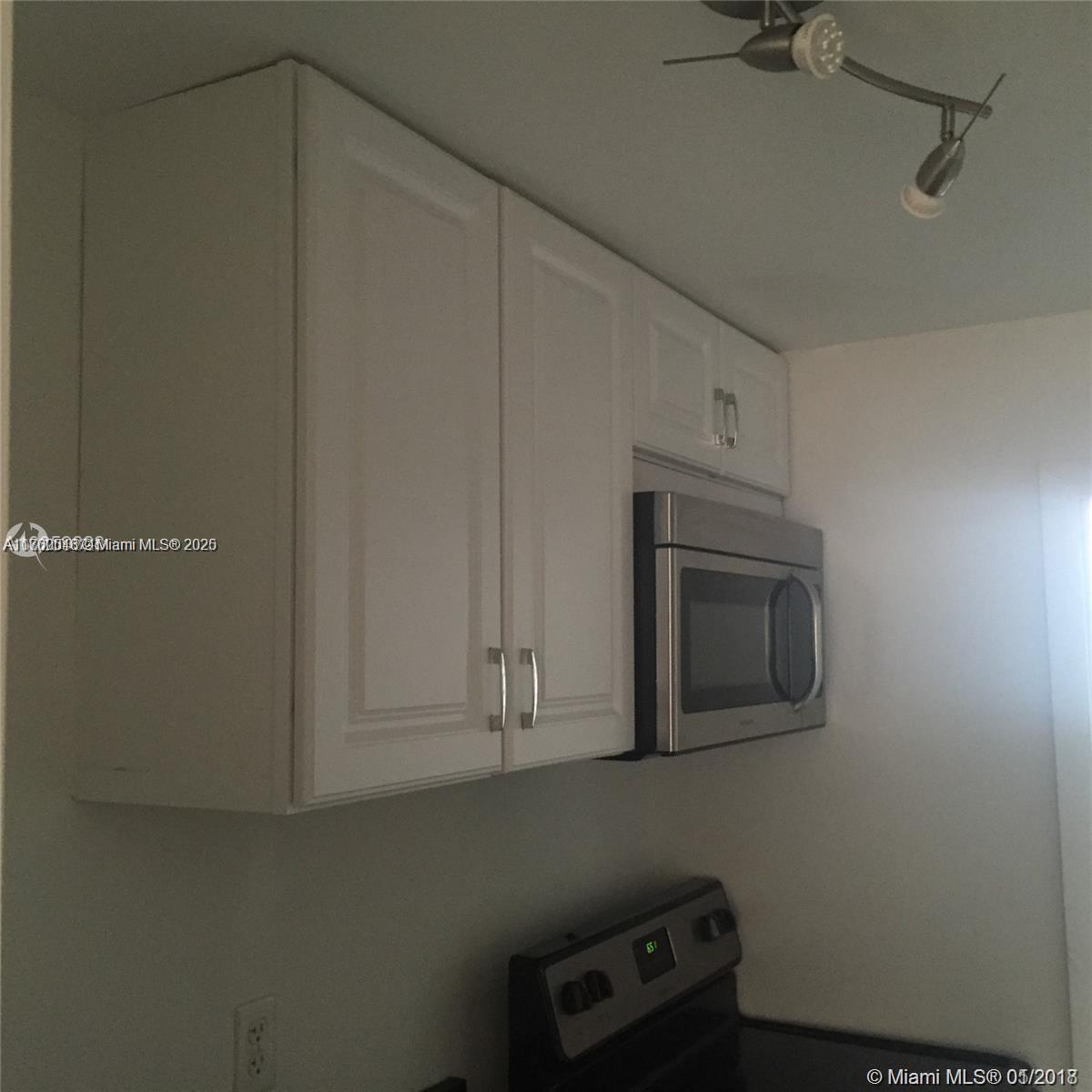 A kitchen features white cabinets, a stainless steel microwave, and a black electric stove — 918 Jefferson Ave # 2, Miami Beach FL 33139, MIAMI BEACH, FL