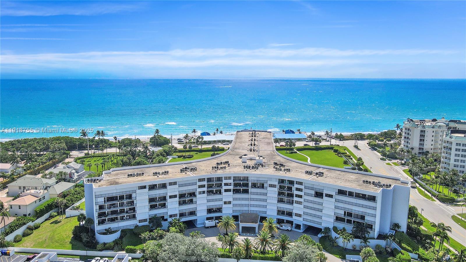 An aerial view shows a multi-story white residential building situated near the ocean — 1300 S Highway A1a # 227, Jupiter FL 33477, JUPITER, FL