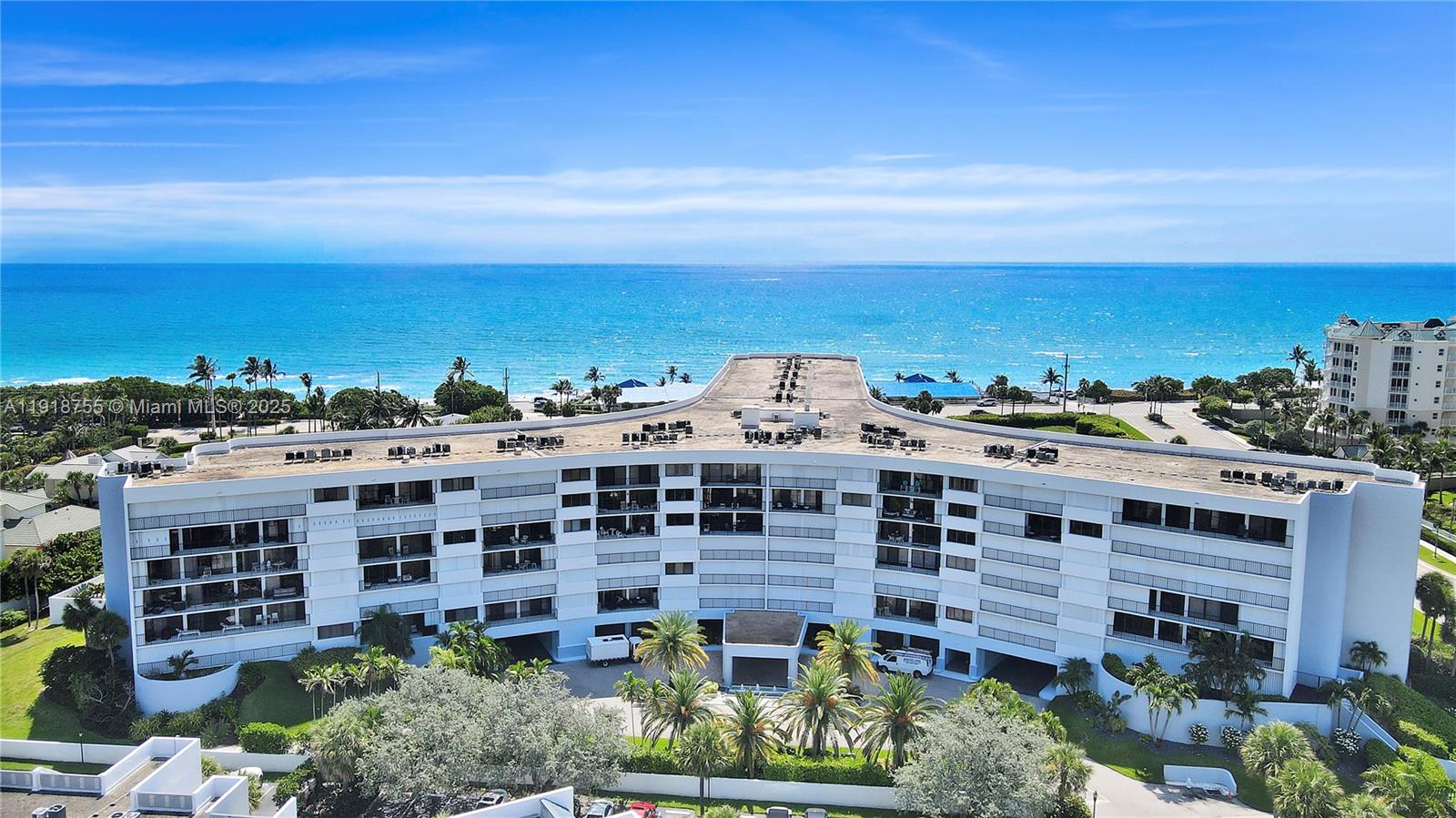 An aerial view shows a multi-story white residential building situated near the ocean — 1300 S Highway A1a # 227, Jupiter FL 33477, JUPITER, FL