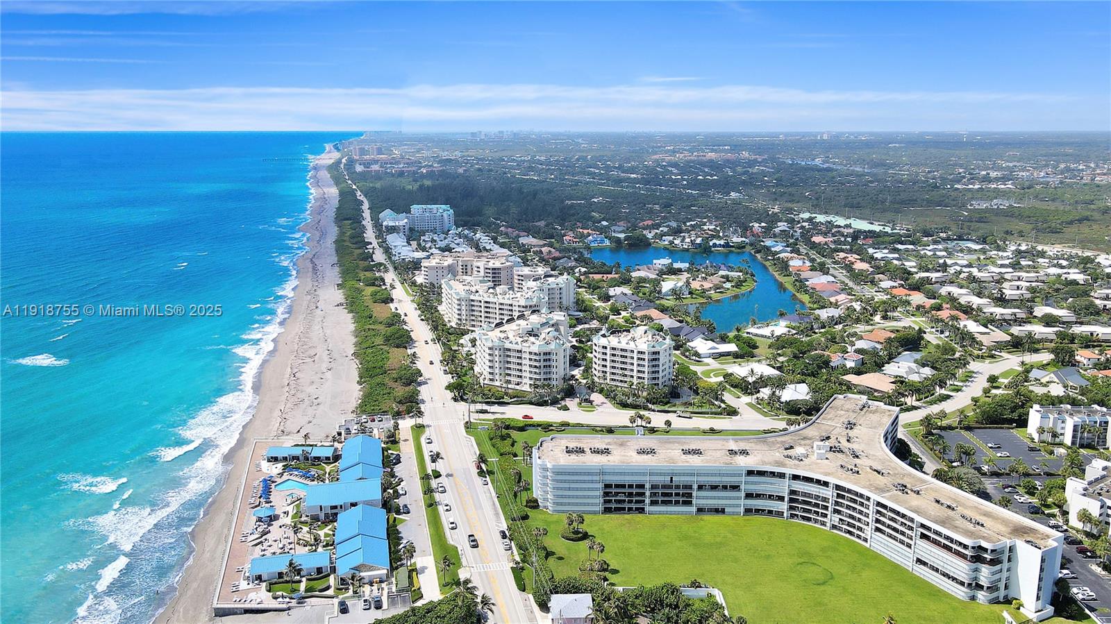 An aerial view shows a coastal residential area with beachfront buildings and a nearby lake — 1300 S Highway A1a # 227, Jupiter FL 33477, JUPITER, FL