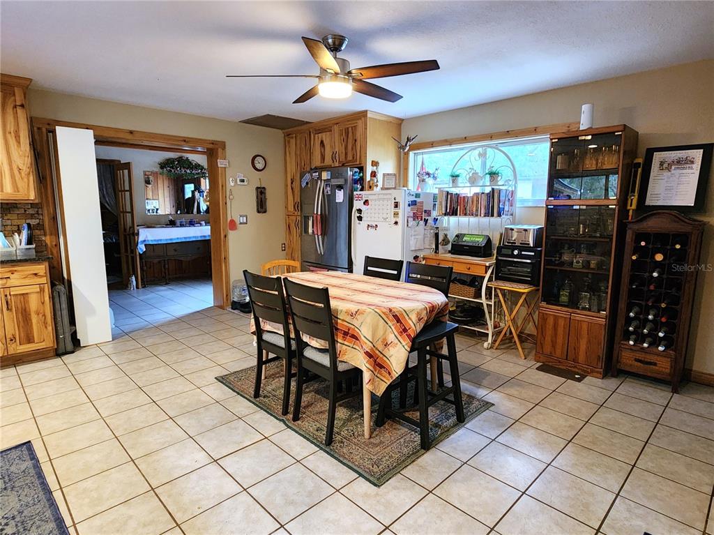A kitchen with tile floors, wooden cabinets, a dining table, and a glass-front display cabinet — 13501 NE 245TH STREET ROAD, FORT MC COY, FL