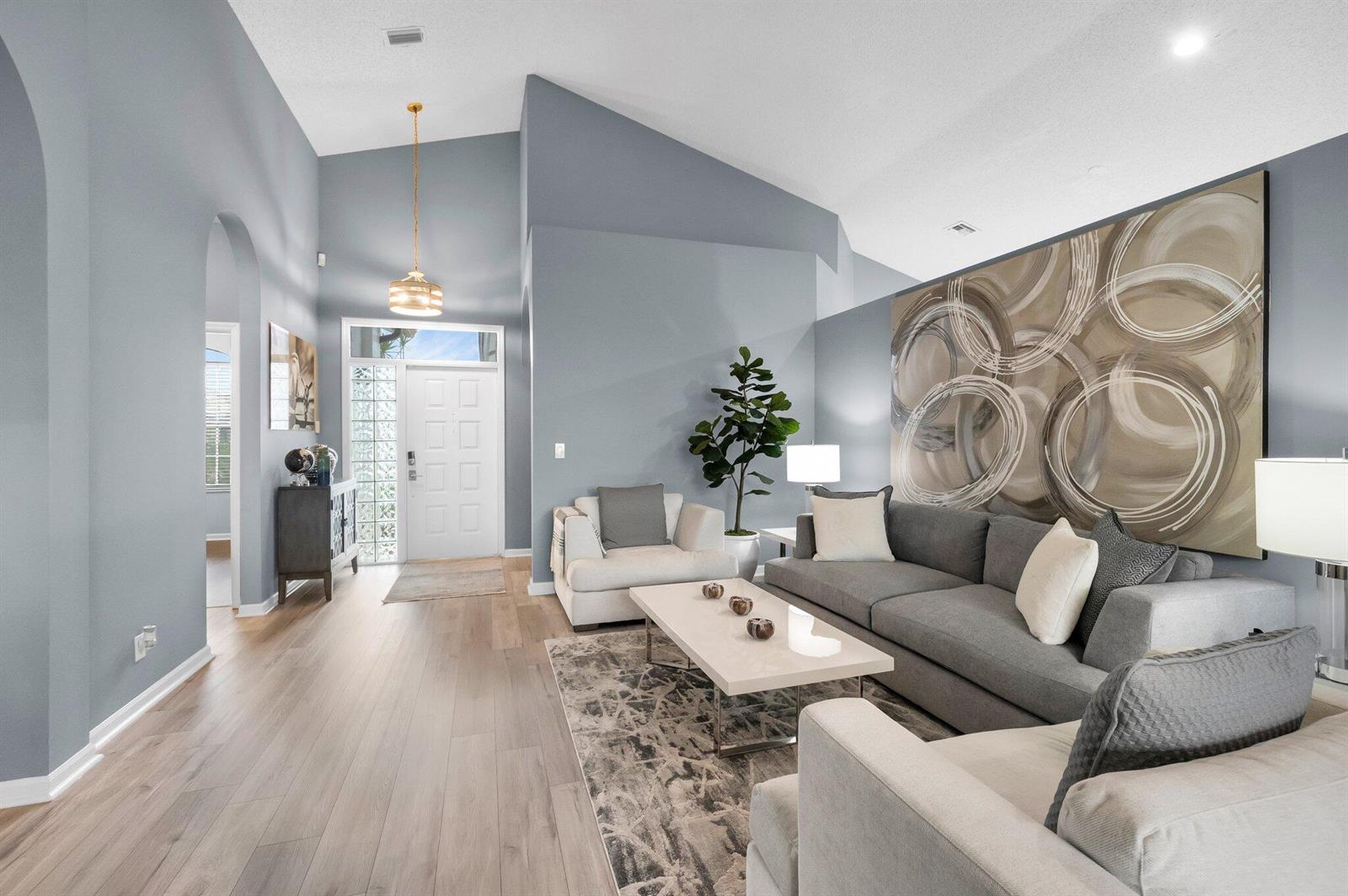 A living room features vaulted ceilings, gray walls, a large abstract painting, and hardwood floors — 10393 Lexington Circle S, Boynton Beach FL 33436, BOYNTON BEACH, FL
